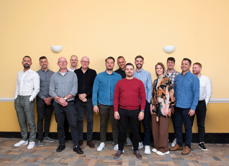 Teamfoto av medarbeidere som jobber med workforce management, vaktplanlegging og timeregistrering for effektiv bemanning og drift.