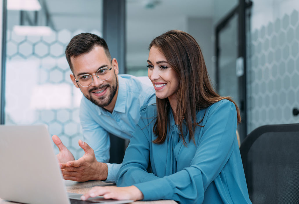 To kolleger samarbeider ved en laptop og viser hvordan digitale verktøy støtter onboarding, vaktplan og teamproduktivitet.