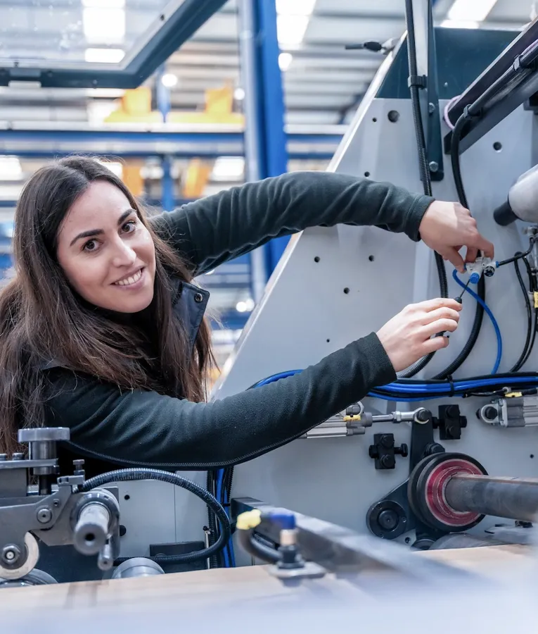 Kvinnelig tekniker jobber med maskinutstyr i fabrikk, planlagt i skift med workforce management og oppgavebasert tidsregistrering i produksjonen.