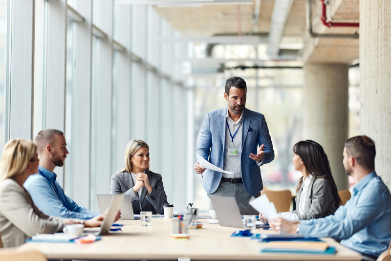 Leder som holder et møte med teamet sitt om implementering av en AI-basert Workforce Management-løsning for å forbedre vaktplanlegging, timeregistrering og ressursoptimalisering.