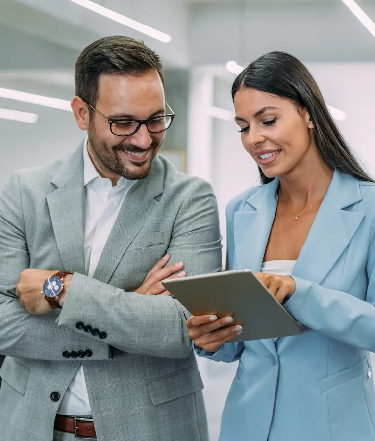 To profesjonelle ser på bemanningsdata på et nettbrett, og viser samarbeid om digital vaktplanlegging og mobil arbeidsstyring.